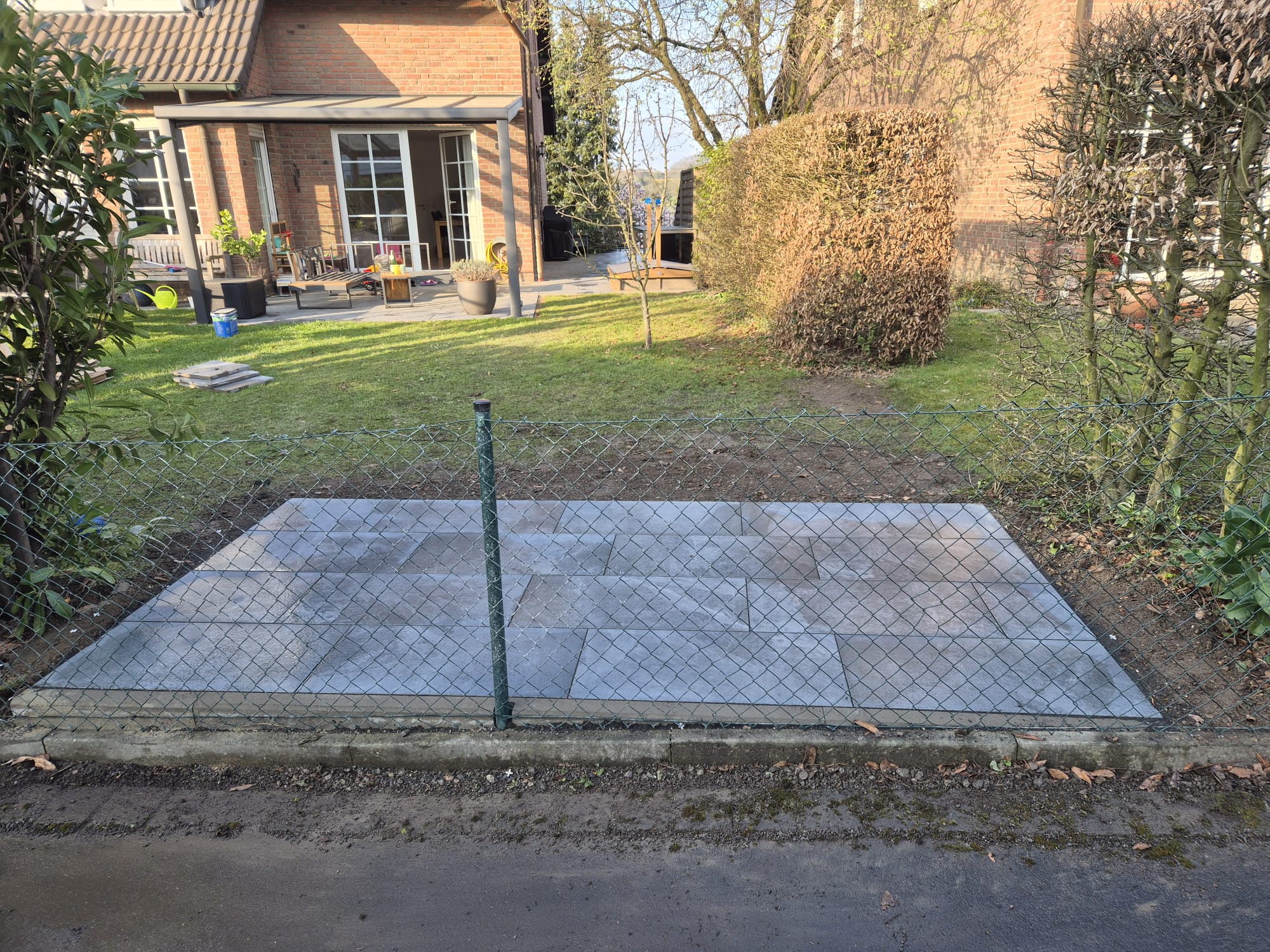 Terrassenbau Langenfeld – Neue ebene Terrasse nach Pflasterarbeiten Neue ebene Terrasse nach Terrassenbau und Pflasterarbeiten in Langenfeld – hochwertige graue Pflastersteine mit Blick auf Haus und Garten