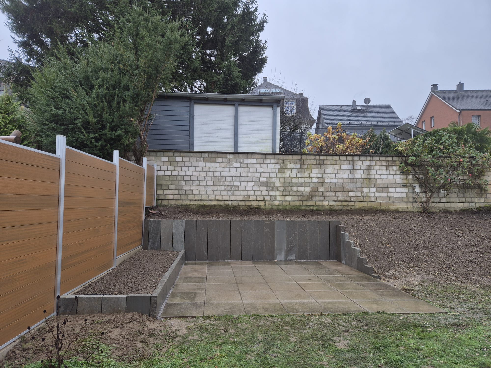 Nachher – Fertiger Terrassenbau nach Pflasterarbeiten in Wuppertal Elberfeld Nachher: Moderne, ebene Terrasse mit Pflastersteinen und Stützmauer nach Terrassenbau und Pflasterarbeiten in Wuppertal Elberfeld durch Syla