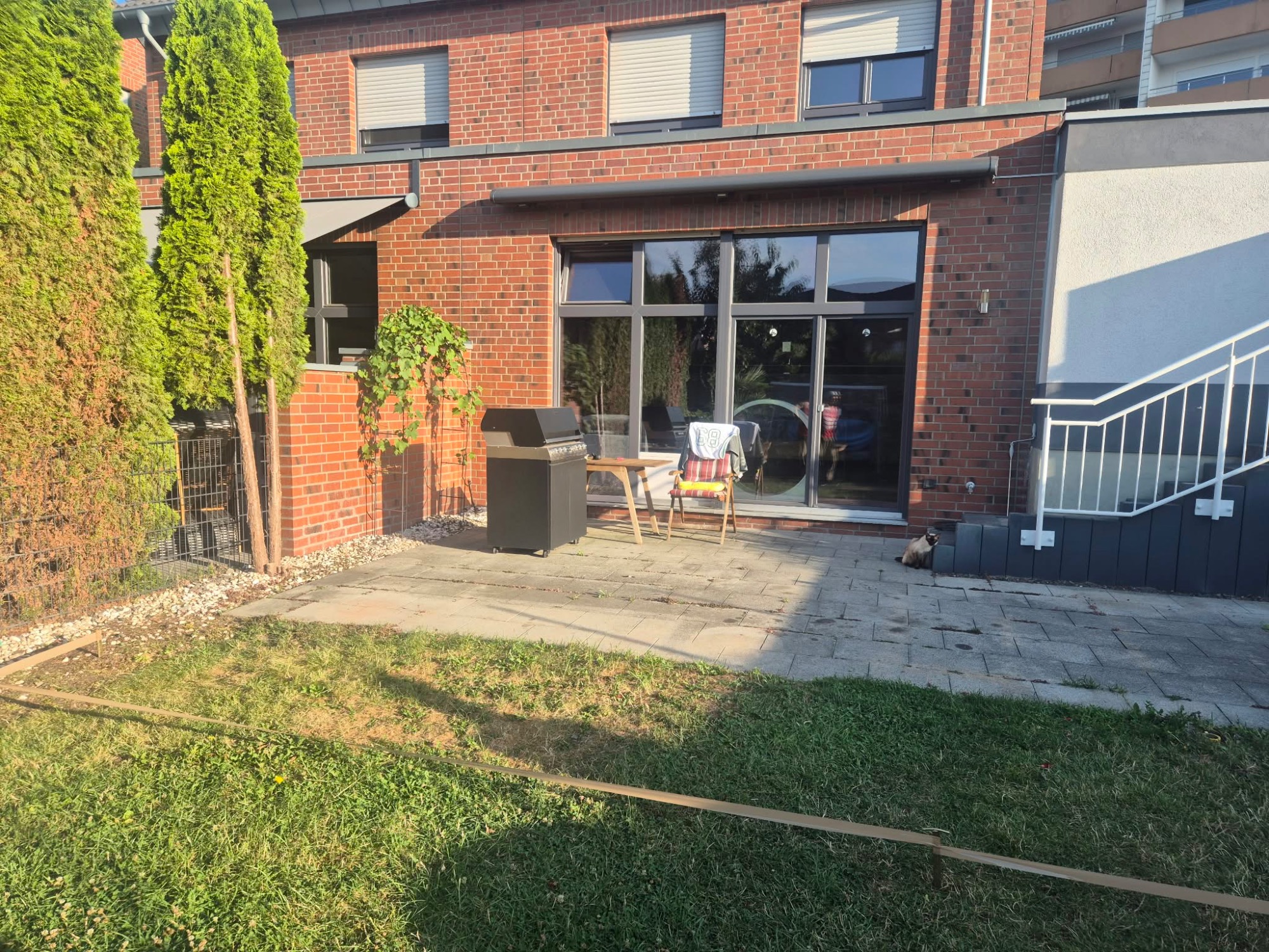 Vorher: Alte Steinterrasse vor dem Umbau zur WPC-Terrasse in Mettmann Alte graue Steinterrasse mit Grill und Gartenmöbeln vor dem Terrassenbau in Mettmann – Ausgangssituation für die neue WPC-Terrasse
